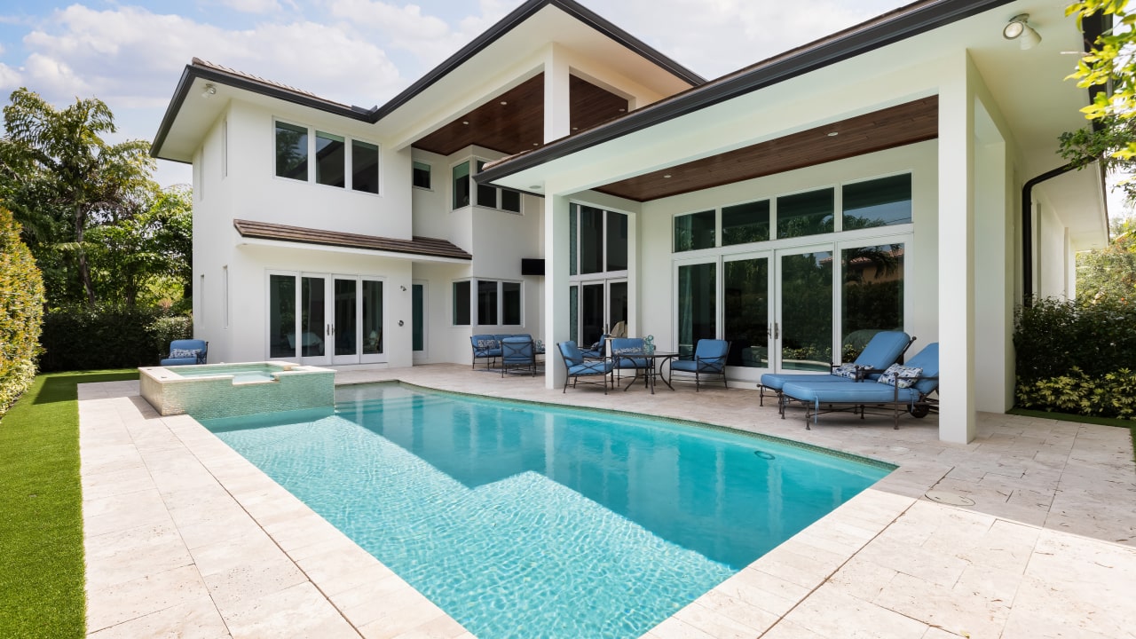 Spacious white home with pool and patio, showcasing window tint.