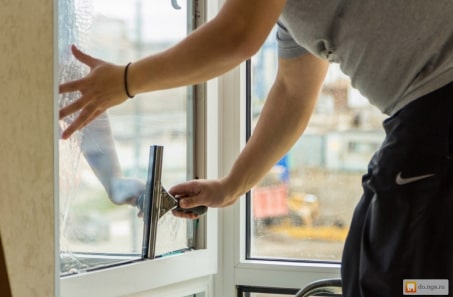 A person cleaning a window with a window cleaner, ensuring a clear and spotless view.